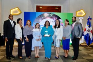 miembros del equipo de la Dirección de Licitaciones y Contratos Públicos del Indotel muestran el reconocimiento. 