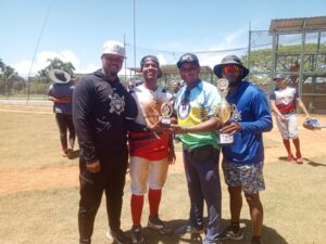Yonkairo Ramírez recibe el trofeo de más valioso de parte de Osiris Reynoso junto a los entrenadores Bryan Lizardo y Alberto Triunfel de Blanco.